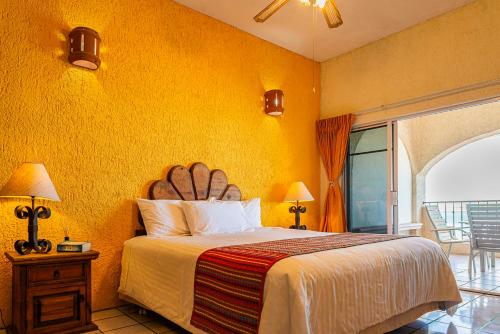 1 dormitorio con cama y pared amarilla en Las Gaviotas Condo-Hotel La Paz BCS, en La Paz