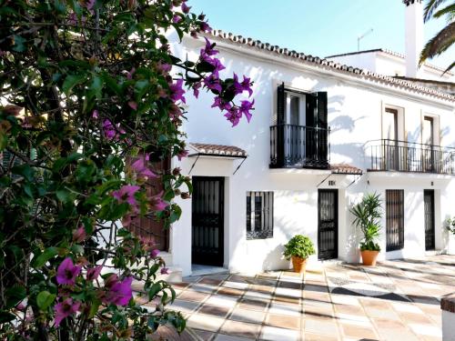 Biały dom z fioletowymi kwiatami przed nim w obiekcie Palm House 10 w mieście Benalmádena