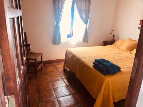 a bedroom with a bed with a yellow sheet and a window at Refugios del Callejón in San Carlos