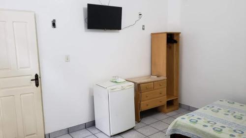 a small room with a refrigerator and a tv on the wall at Suítes em Parintins in Parintins