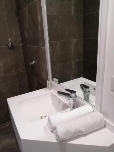 lavabo con espejo y toalla blanca en Vive Place, en Aguascalientes
