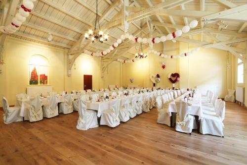 - une salle de banquet avec des tables et des chaises blanches dans l'établissement Bürgerhaus auf dem Hasenberg, à Gützkow