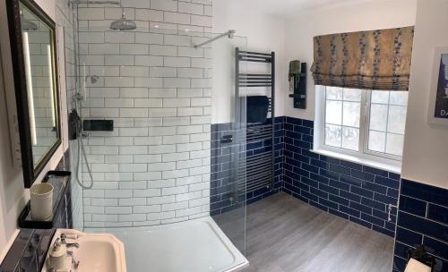 uma casa de banho com um lavatório e um chuveiro com azulejos azuis em Seven Stars Boutique Guesthouse em Exeter