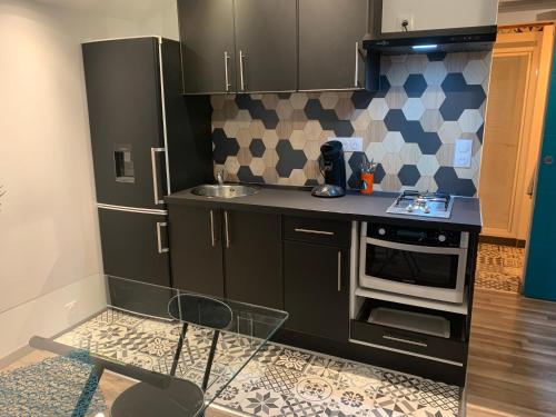 a small kitchen with black cabinets and a stove at T1, spa privé accès piscine sauna in Moëlan-sur-Mer