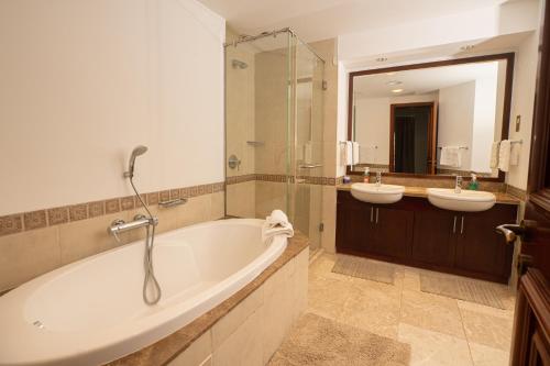 a bathroom with two sinks and a tub and a mirror at Gorgeous 2BR in Fairmont in Dubai