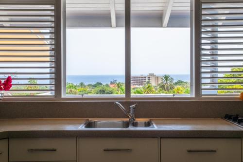 een keuken met een wastafel en 3 ramen bij Piscadera Bay Resort 104 in Willemstad