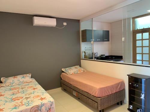 ein kleines Schlafzimmer mit einem Bett und einem Spiegel in der Unterkunft Sunset Maresias- Casas e Chalés C1 in Maresias