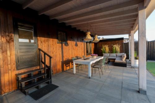 a patio with a table and chairs and a couch at Hip huisje aan de Maas in Lith