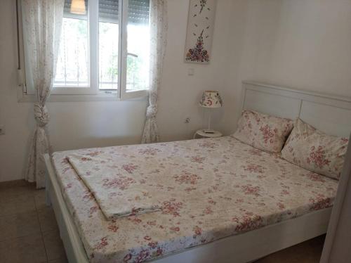 ein Schlafzimmer mit einem Bett mit geblümter Tagesdecke und einem Fenster in der Unterkunft ΔΕΣΠΟΙΝΑ in Néa Péramos