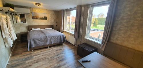 een slaapkamer met een bed en een groot raam bij B&B Mackenzieplaats in Wilp