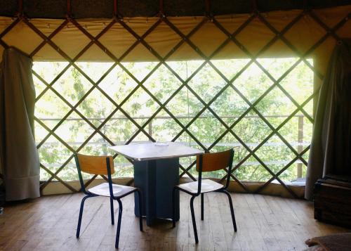 a table and chairs in a yurt with a window at le cri de la yourte in Saint-Urcisse