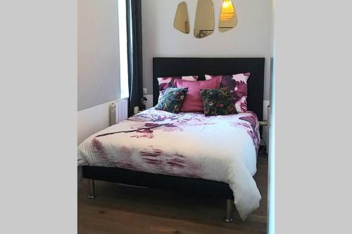 une chambre avec un lit avec des oreillers roses et violets dans l'établissement T2 cosy - gare, plage et intramuros à pied, à Saint-Malo