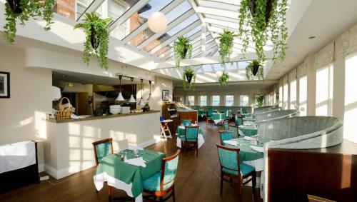 a restaurant with green tables and chairs and windows at The Maypole at Wellow in Ollerton
