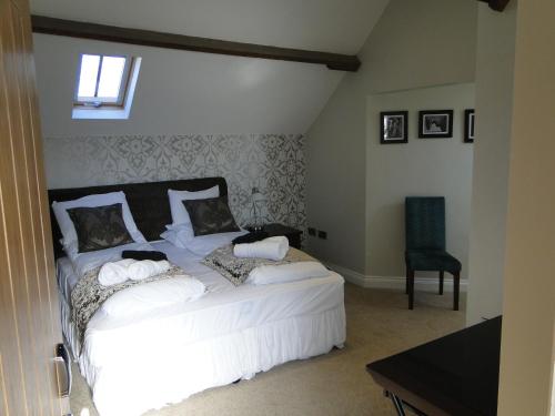 a bedroom with a white bed and a chair at The Maypole at Wellow in Ollerton