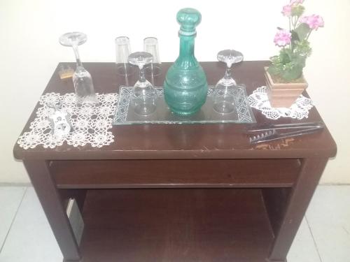 a table with a green vase and glasses on it at Pousada Lírio in Campos dos Goytacazes