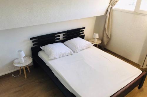 een slaapkamer met een groot wit bed met twee kussens bij Résidence Port Soleil Duplex T3 46 m2 climatisé in Gruissan
