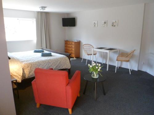 a hotel room with a bed and a red chair at Bosrand81 in Hechtel