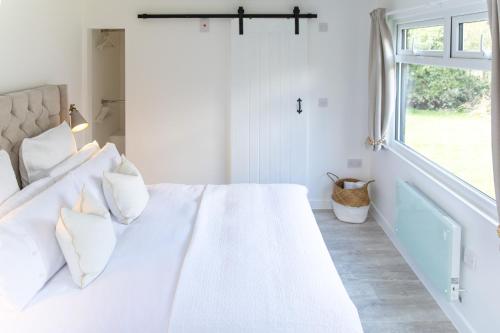 a white bed in a room with a window at The Nook in West Mersea