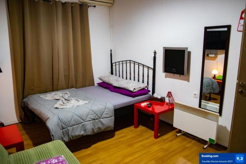Habitación pequeña con cama y TV. en The Zen Apartment Athens, en Atenas