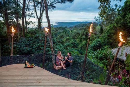 Ein Mann und eine Frau sitzen auf einem Gehweg im Wald in der Unterkunft Selva Armonia Immersive Jungle Resort in Uvita