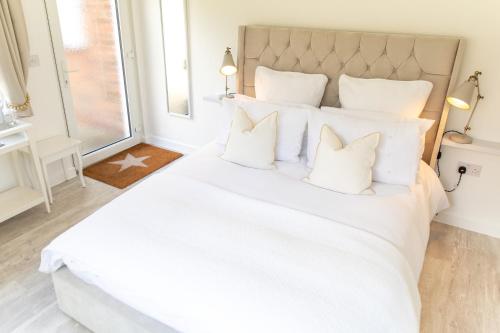 a white bedroom with a large white bed with white pillows at The Nook in West Mersea