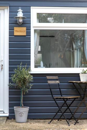 a sign on a blue house with a chair and a window at The Nook in West Mersea