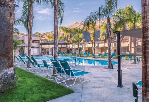 a pool with chairs and palm trees in a resort at WorldMark Palm Springs in Palm Springs