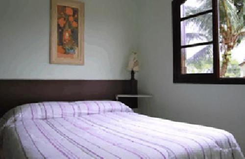 a bedroom with a bed with a purple striped blanket at Hotel Pousada do Comendador in Guarujá