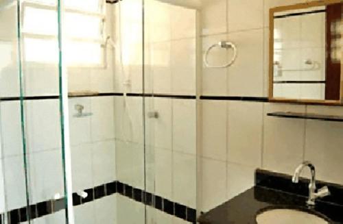 a bathroom with a shower and a sink and a mirror at Hotel Pousada do Comendador in Guarujá