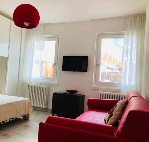 ボルミオにあるGloria Holiday Home Bormioのリビングルーム(赤いソファ、テレビ付)
