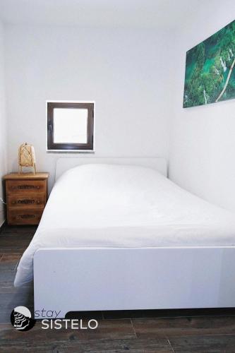 a white bed in a bedroom with a window at Casa do Ferreiro in Sistelo