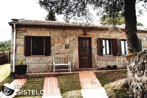 uma casa de pedra com uma porta e uma árvore em Casa do Ferreiro em Sistelo