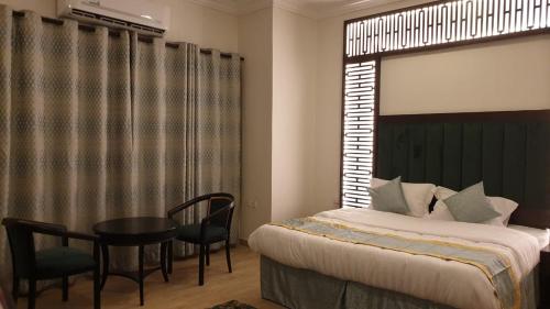 a bedroom with a bed and a table and chairs at الزمردة للشقق المخدومة in Ash Shuqayq