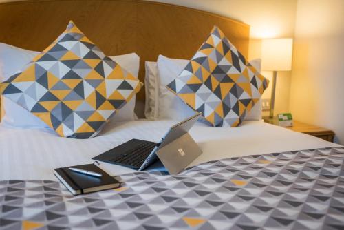 a laptop computer sitting on top of a bed with pillows at Holiday Inn Manchester West by IHG in Manchester
