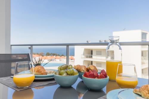 a table with a plate of food and two glasses of orange juice at NazOndas Ap in Nazaré