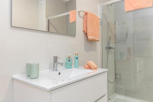 biała łazienka z umywalką i prysznicem w obiekcie NazOndas Ap w mieście Nazaré