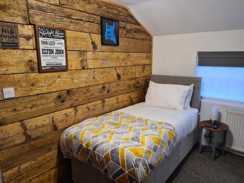 Un dormitorio con una pared de madera y una cama en Carpenters Arms en Boston