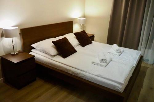 a bedroom with a bed with white sheets and brown pillows at Sarmacka Apartment in Wilanów in Warsaw