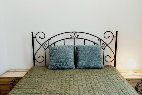 a bed with a metal headboard and two blue pillows at Apartament 4 Żagle in Giżycko