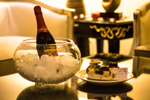 a bottle of wine in a glass next to a piece of cake at Rest Night Serviced Apartments- AlHamra in Riyadh