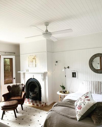 a bedroom with a bed and a chair and a fireplace at La Perouse Lorne in Lorne
