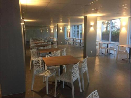 a dining room with tables and white chairs and tablesktop at Evian Thermas Residence - Caldas Novas in Caldas Novas