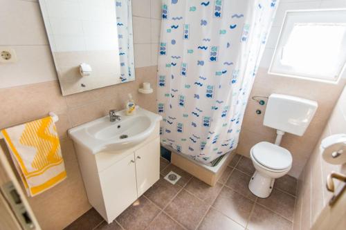 ein Badezimmer mit einem Waschbecken, einem WC und einem Duschvorhang in der Unterkunft House Dolphin in Tkon
