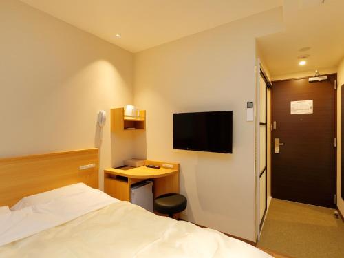 a hotel room with a bed and a desk and a tv at Hotel Grand Terrace Obihiro Annex in Obihiro