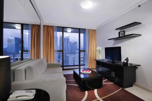 a living room with a white couch and a television at Horison Ultima Suite & Residences Rasuna Jakarta in Jakarta