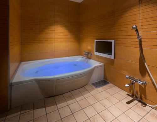 a large bath tub in a bathroom with a tv at HOTEL FINE - INTO THE PREMlUM - in Okazaki
