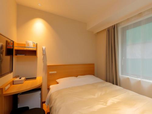 a bedroom with a bed and a desk and a window at Hotel Grand Terrace Obihiro Annex in Obihiro