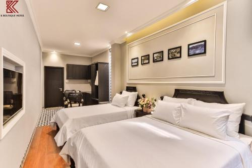 two beds in a hotel room with white sheets at TTR Skypool View Hotel in Da Lat