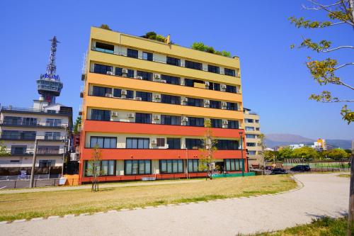 a large apartment building with a tower in the background at Seaside Hotel Mimatsu Ooetei in Beppu