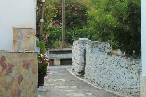 an alley with a stone wall and flowers at Traditional Stone House at Great Location in Koroni